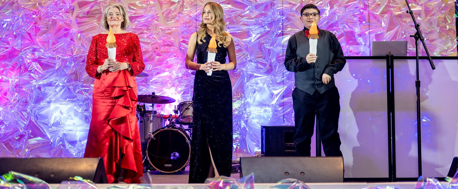 Three people on stage holding up lit torches.